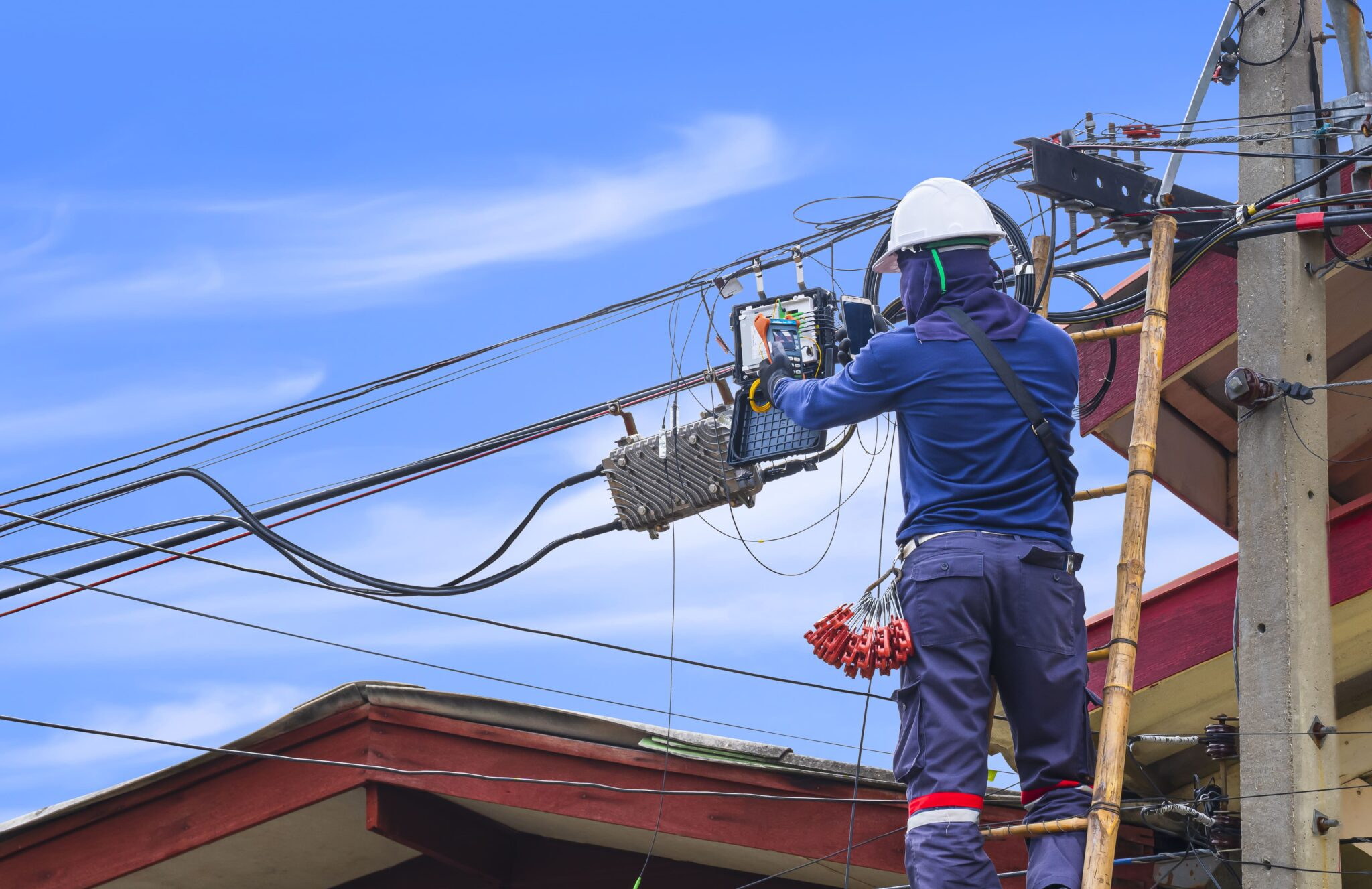 Fibre technician connecting service lines inside an aerial distribution box on a utility pole