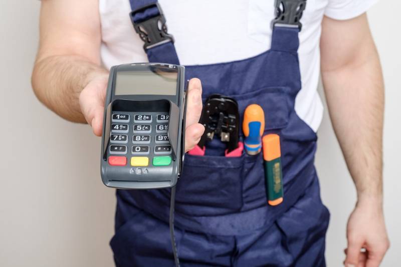 Service technician holding a wired payment terminal with a numeric keypad