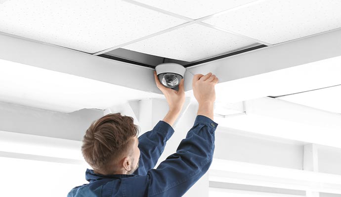 Technician installing a dome security camera in a commercial suspended ceiling