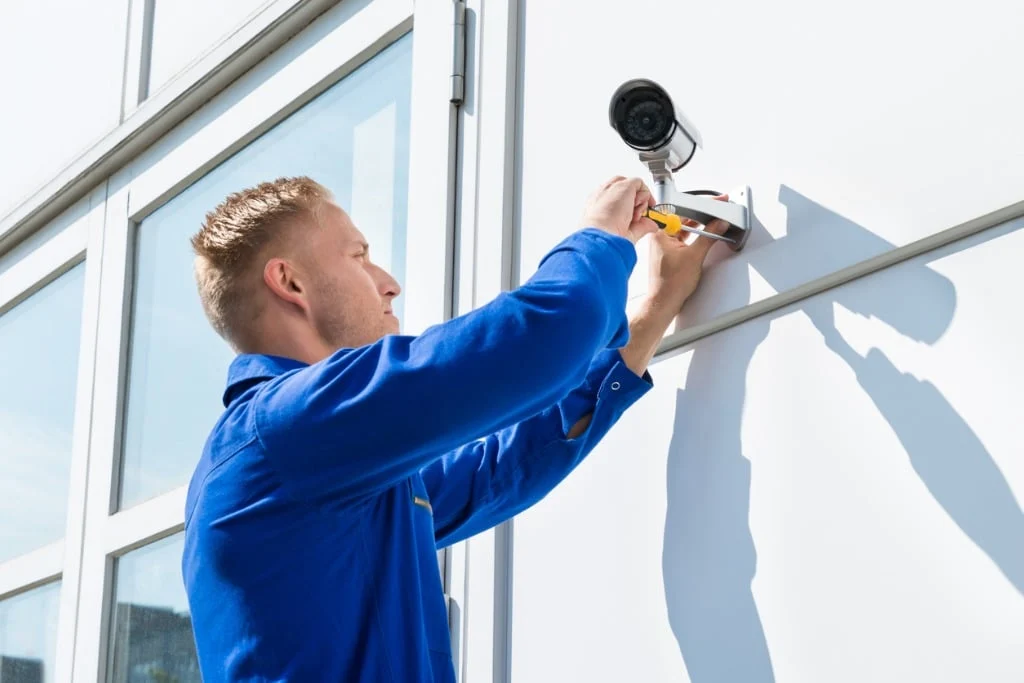 Technician mounting an outdoor security camera on a home exterior wall