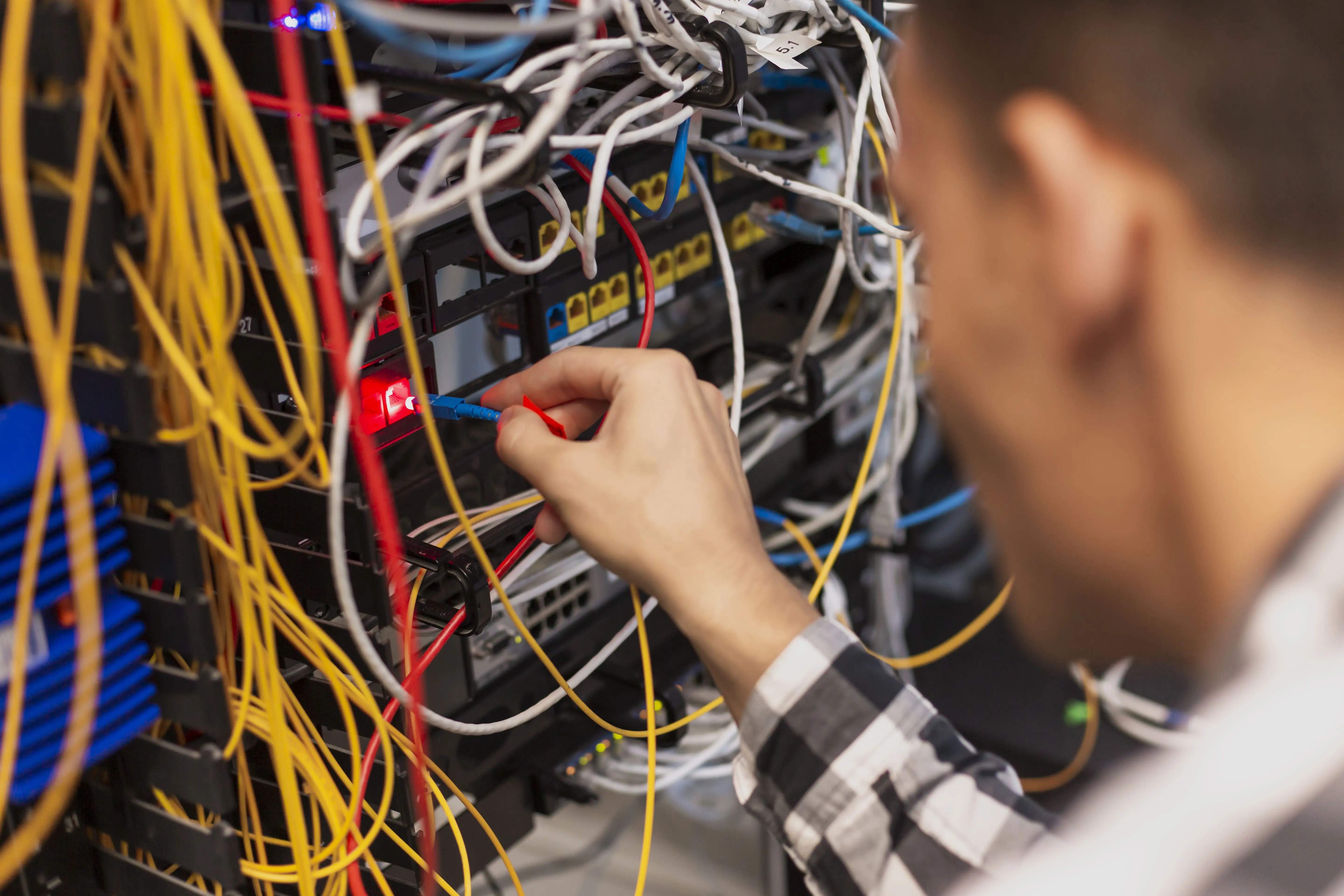 Engineer connecting a fibre patch cord to a network switch during rack migration work
