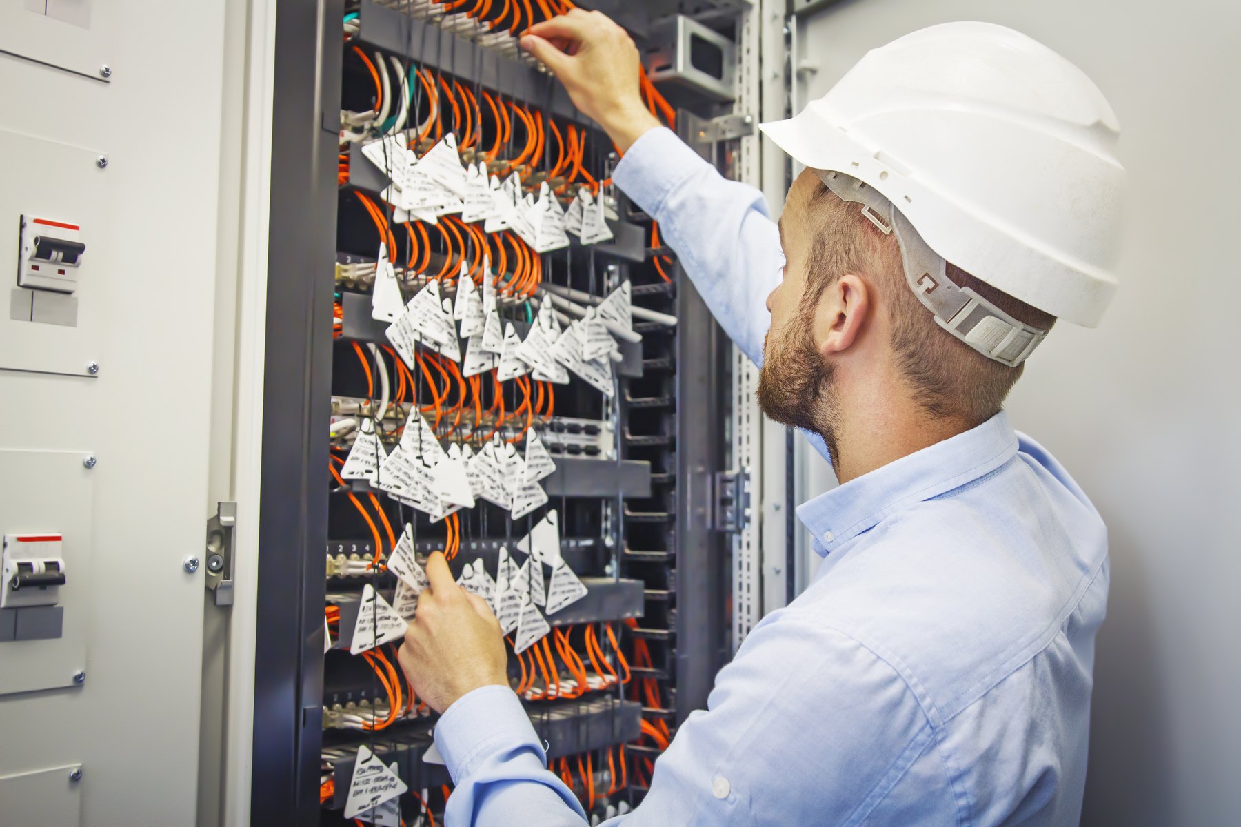 Network engineer working with fibre patch cords inside a communications rack